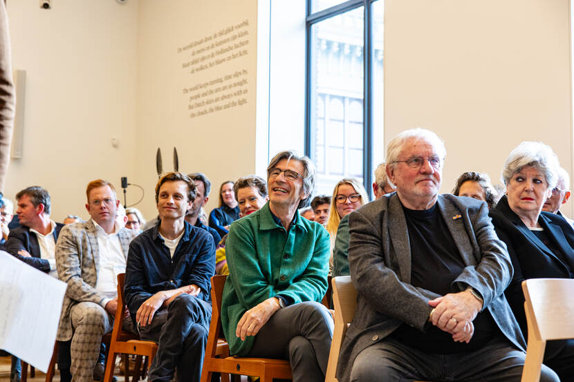 Mensen in de zaal luisteren aandachtig